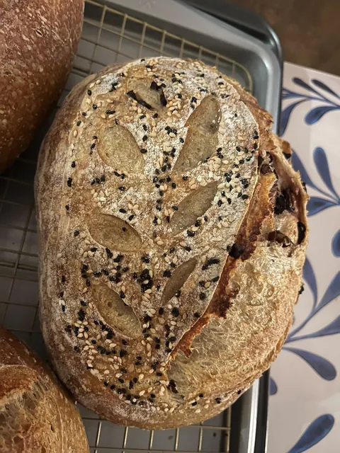 Une miche incisée d’un épi de blé, des graines sur la croûte.