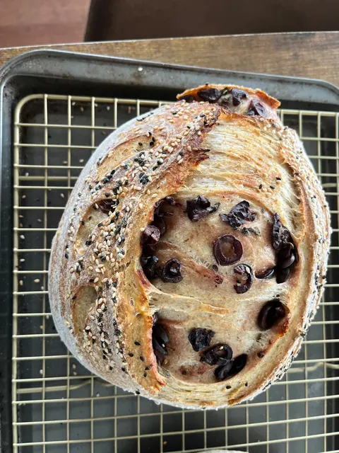 Une miche ronde, des olives noires visibles dans l’incision.